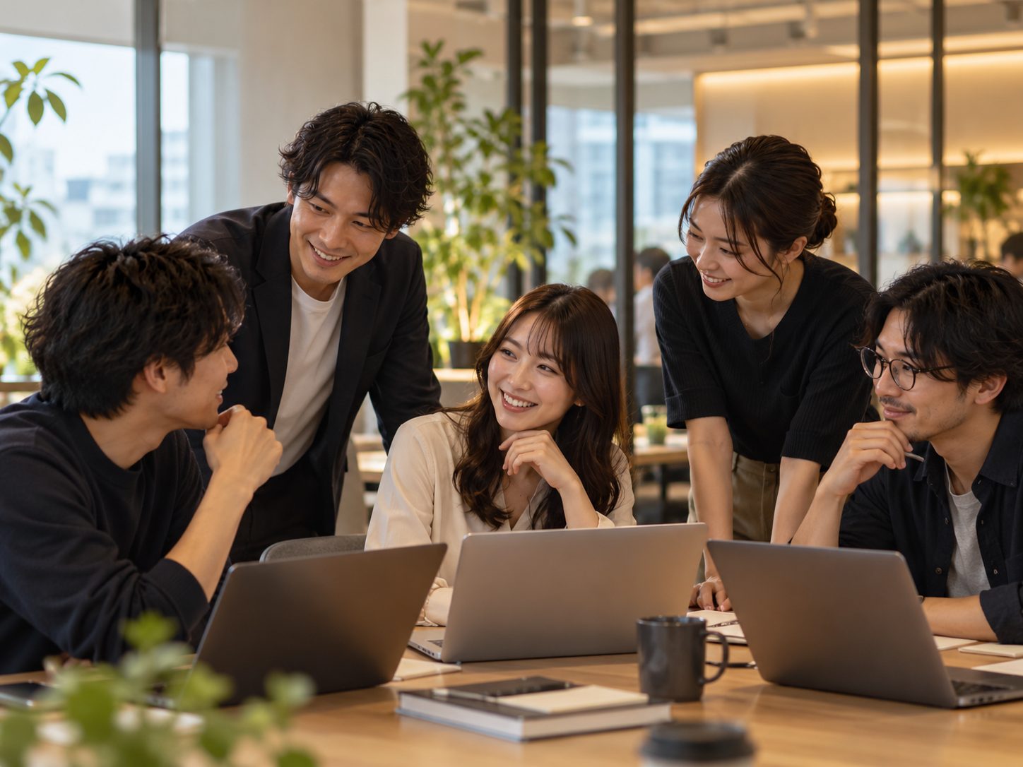 オフィスでノートパソコンを囲んで話すチーム